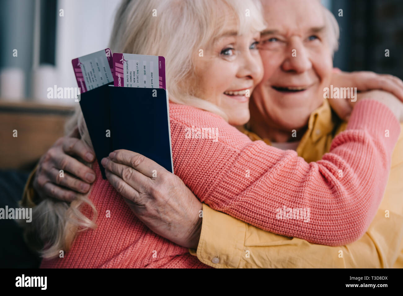 Sorridente coppia senior abbracciando e trattenere aria biglietti con passaporti a casa Foto Stock