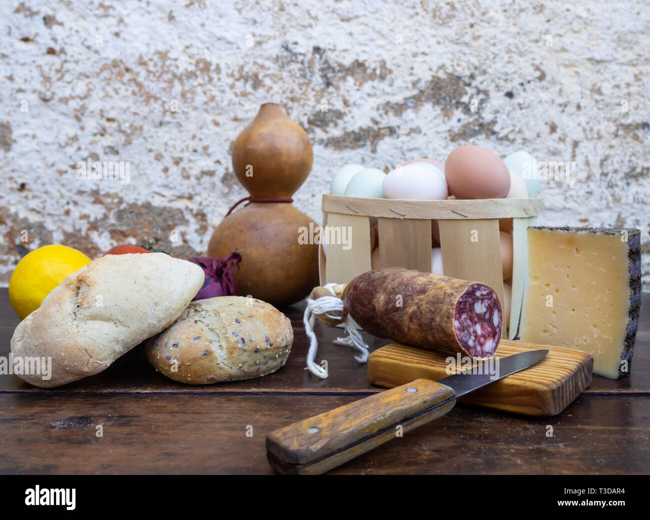 Tradizionale cibo spagnolo su un vecchio tavolo di legno, carne di maiale iberico salsicce, pane, uova, formaggio e verdure e un vecchio coltello Foto Stock