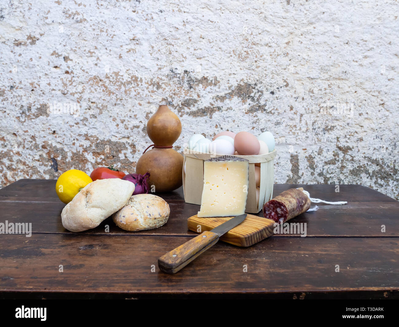 Tradizionale cibo spagnolo su un vecchio tavolo di legno, carne di maiale iberico salsicce, pane, uova, formaggio e verdure e un vecchio coltello Foto Stock