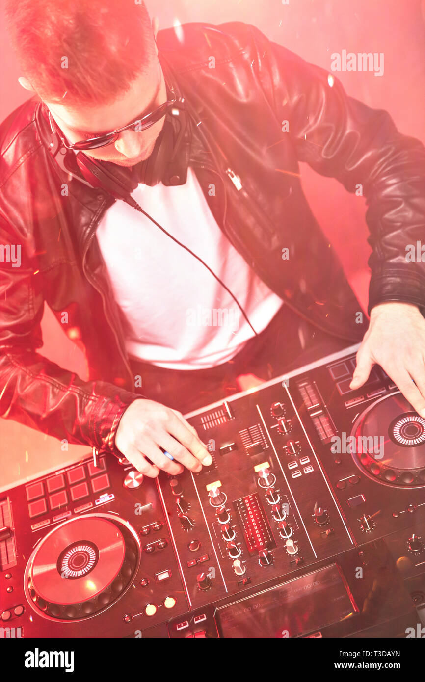 Il mixaggio DJ al party festival con la luce rossa e il fumo in background - Estate vista notturna della discoteca all'interno. La messa a fuoco a portata di mano Foto Stock