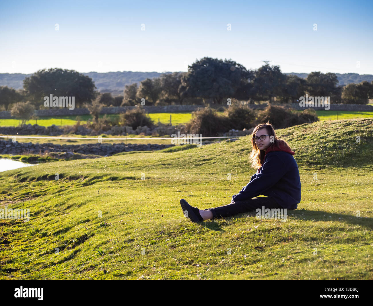 Una ragazza adolescente nel campo in primavera prendendo il sole Foto Stock