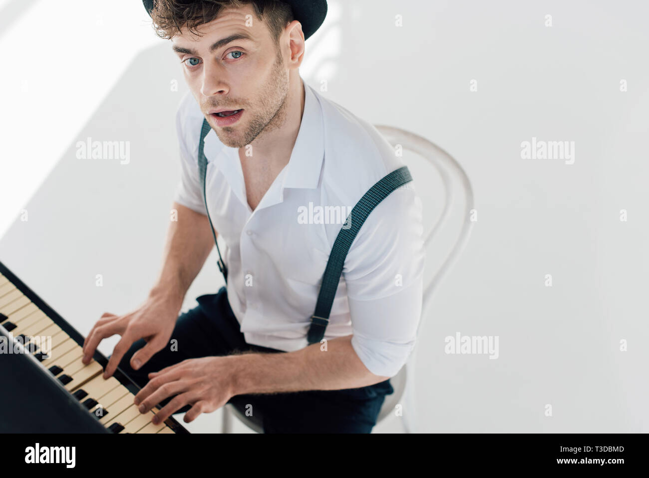 Bello il pianista in camicia bianca e cappello nero suonare il pianoforte  Foto stock - Alamy