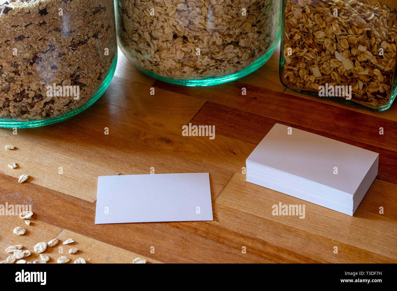 Business card mockup modelli su un tavolo con cosparso di farina di avena - muesli vasi in background Foto Stock