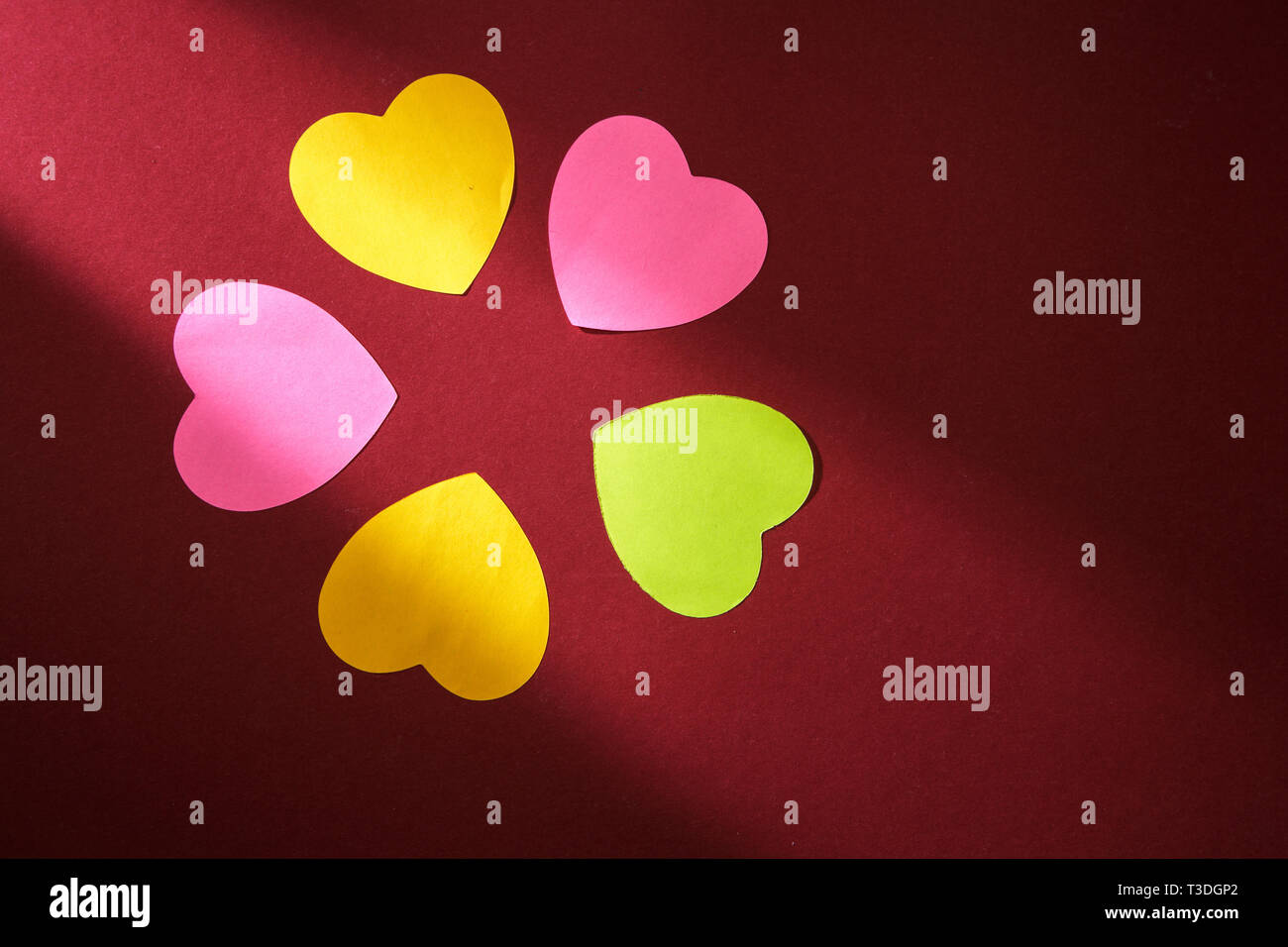 Etichette colorate forma di cuore collocato in un fascio di luce. Carta per il giorno di San Valentino Foto Stock