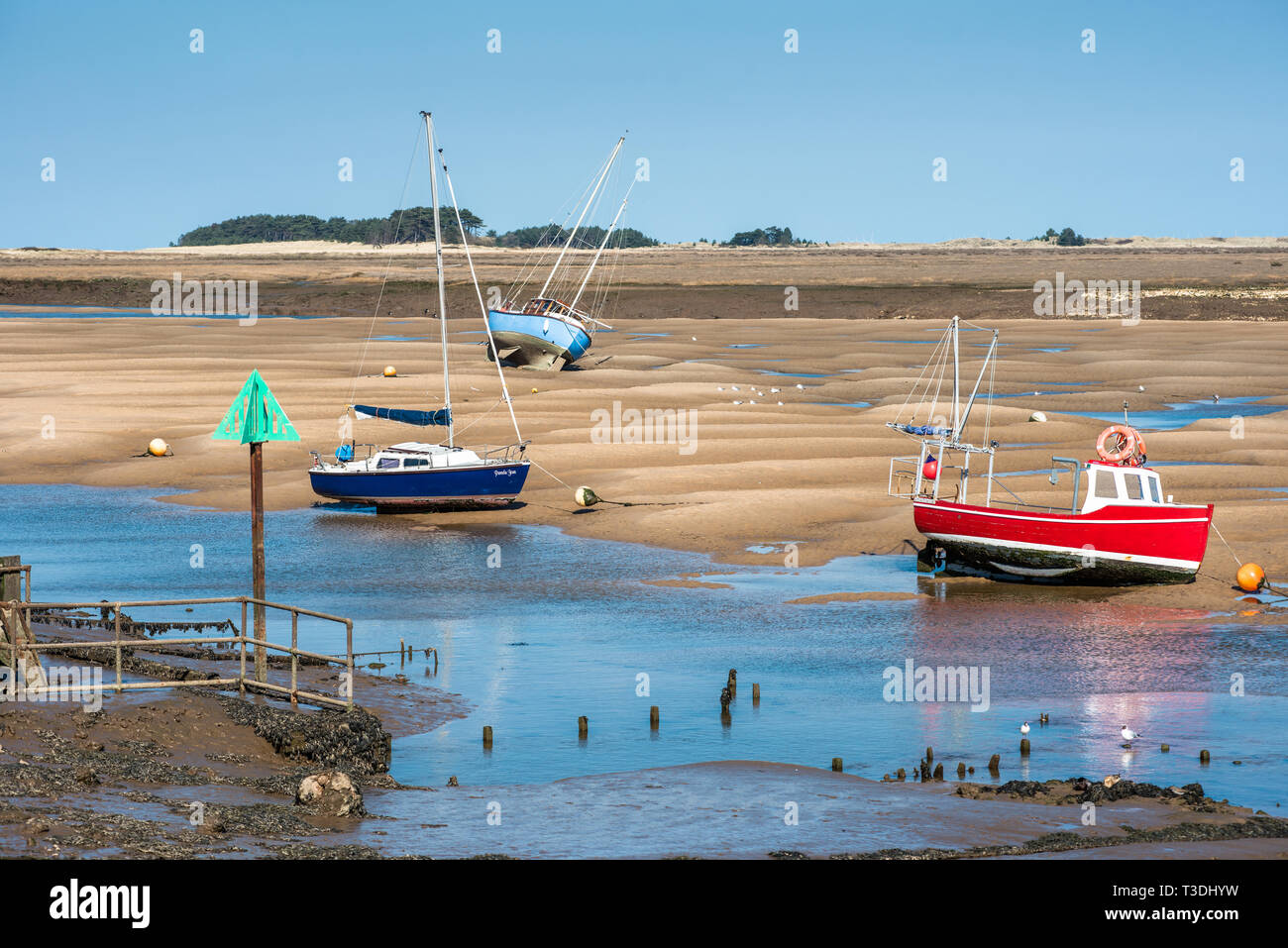 Barche colorate fregata su banchi di sabbia con la bassa marea sulla flotta est estuario del fiume a Wells accanto al mare Costa North Norfolk, East Anglia, Inghilterra, Regno Unito. Foto Stock