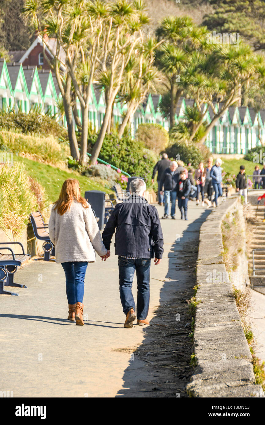 LANGLAND BAY, GOWER, GALLES - Febbraio 2019: uomo e donna camminando mano nella mano lungo la promenade di sole in Langland Bay in Gower penninsula Foto Stock