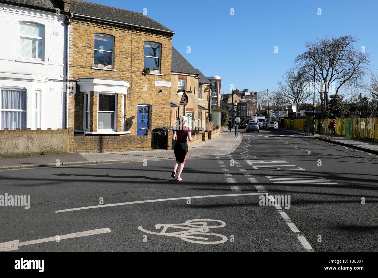 Vista posteriore di una giovane donna che indossa la lycra che corre lungo Pulross Rd all angolo della strada Dalyell case in Brixton a sud di Londra Inghilterra REGNO UNITO KATHY DEWITT Foto Stock