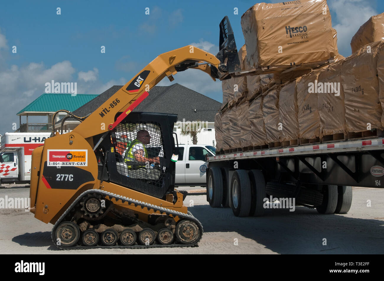 Attrezzature MAECO operatore Scott McMichaels rimuove una pila di HESCO barriere da un carrello all'estremità ovest del Dauphin Island, Alabama. Foto Stock
