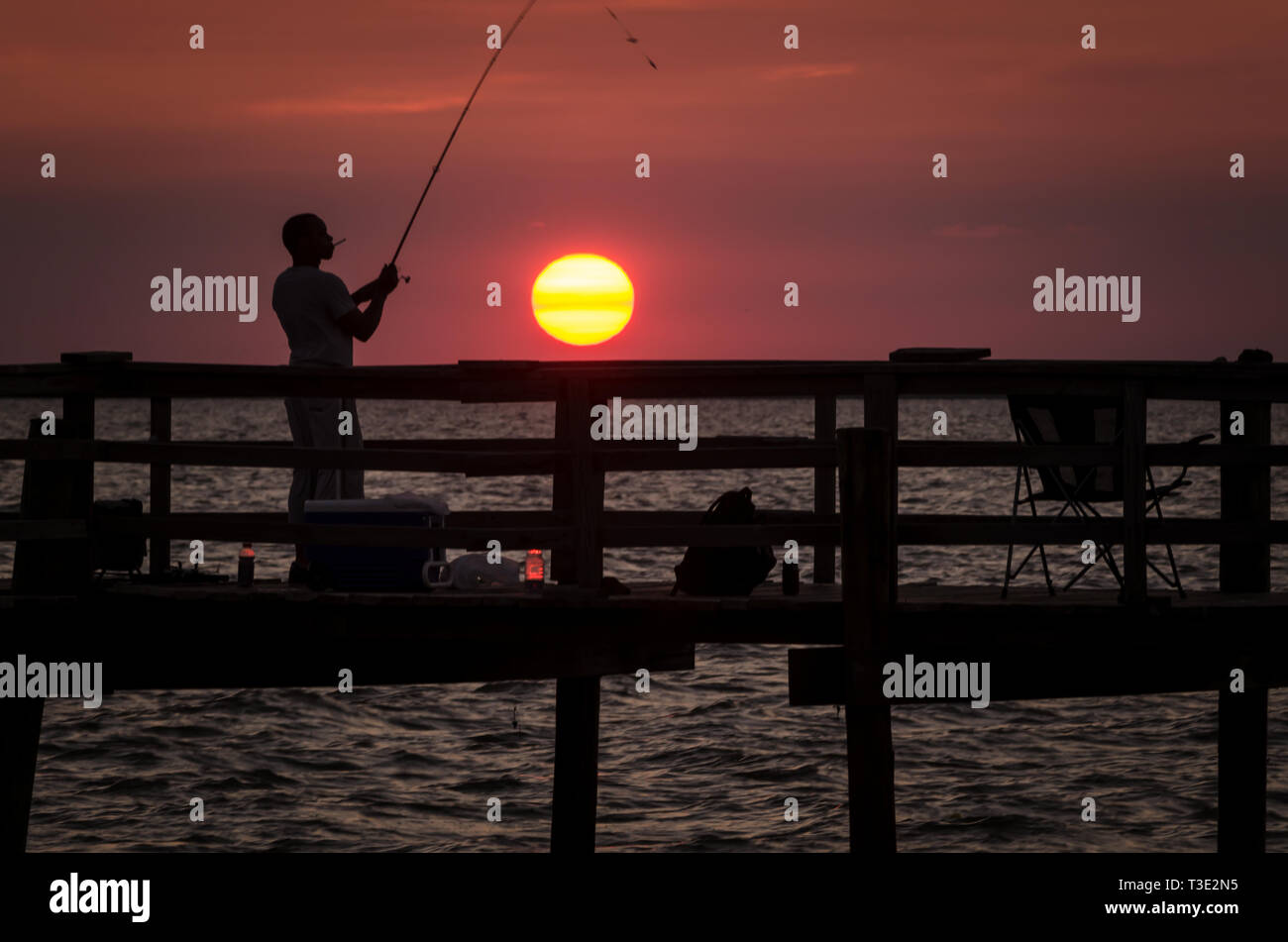 Un uomo si stagliano da sole di setting come egli pesci, 1 luglio, 2013, a Cedar Point Molo Pesca in Alabama Gulf Coast. Foto Stock