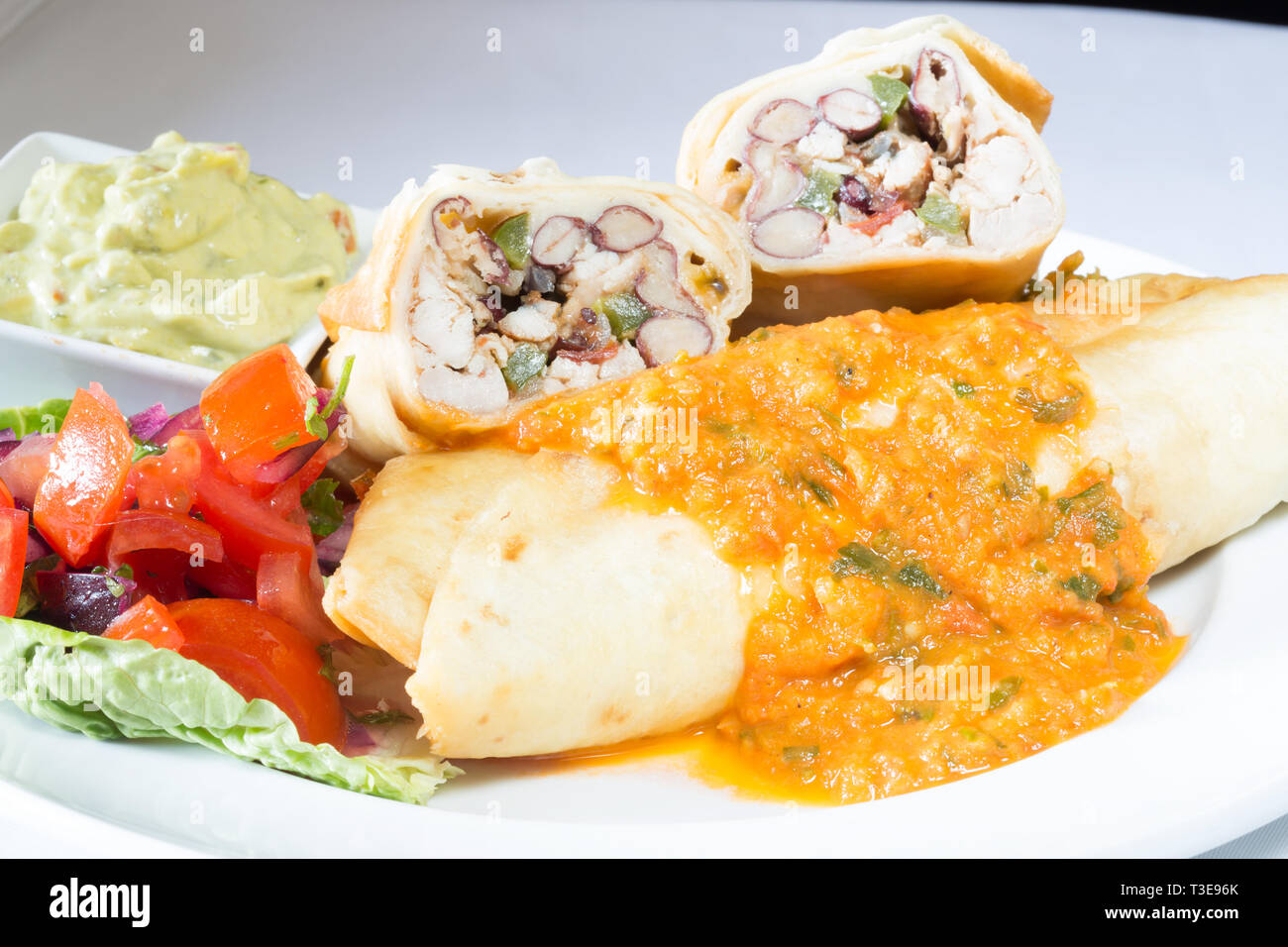 Pollo alla messicana e ri-fagioli fritti Chimichanga con salsa di pomodoro e peperoncino Salsa Foto Stock