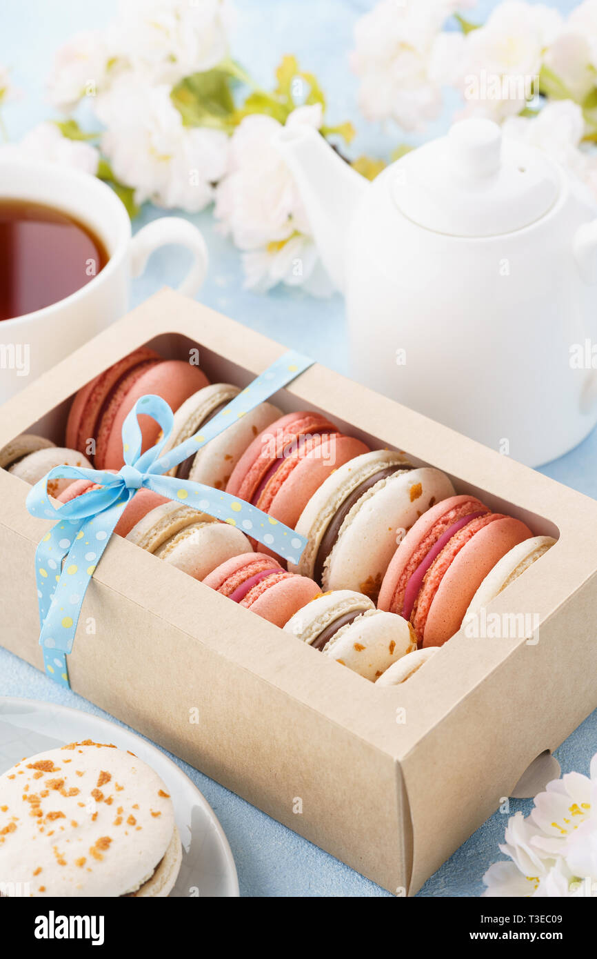 Confezione regalo con french macarons e tè per dessert. Fiori in background. Foto Stock