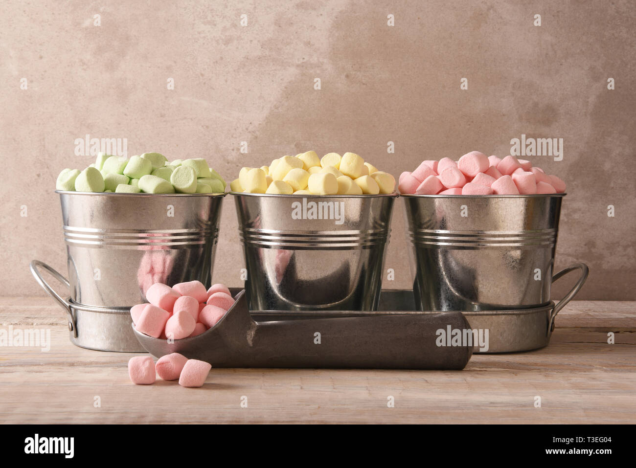 Tre piccoli secchi pieni di marshmallows colorati con un gelato scoop e rosa marshmallows in primo piano. Foto Stock