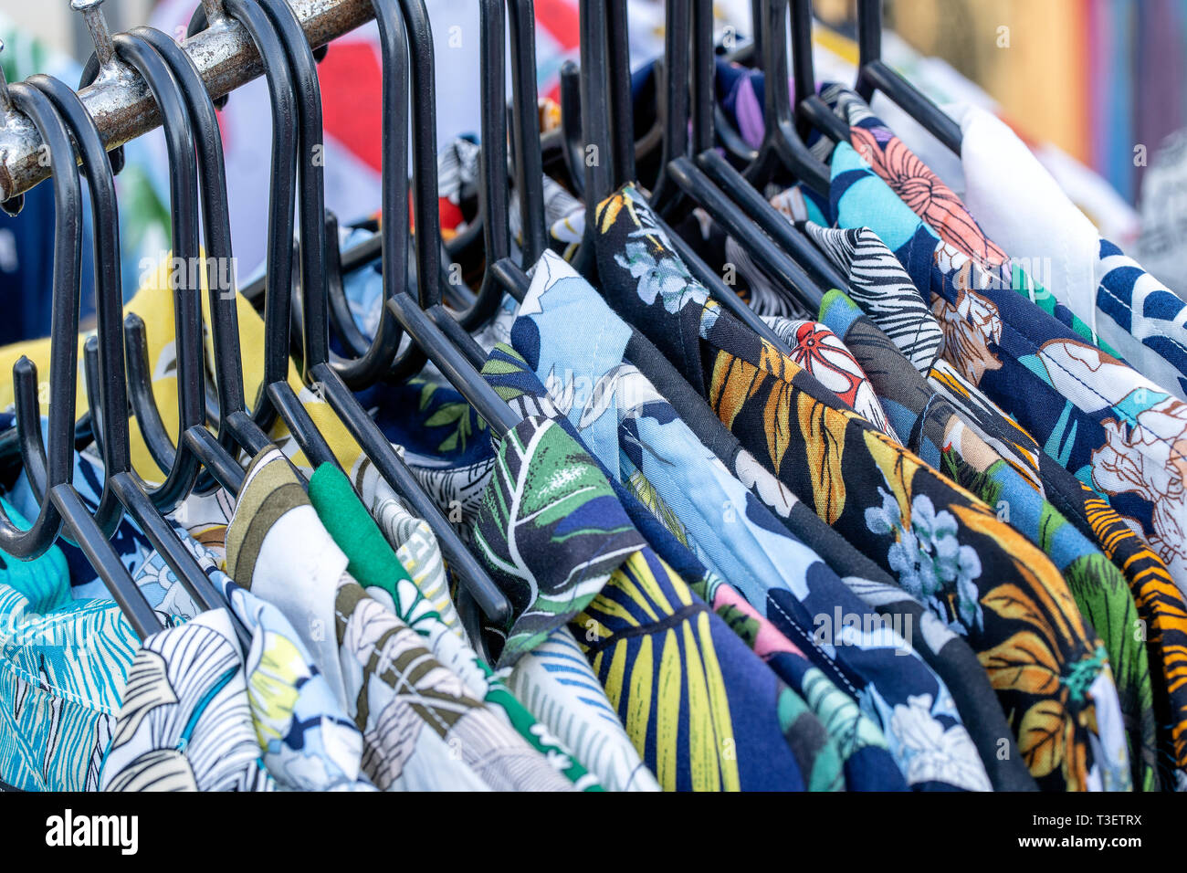 Estate colorati magliette sulle staffe per la vendita nel locale mercato di strada in Thailandia, close up Foto Stock