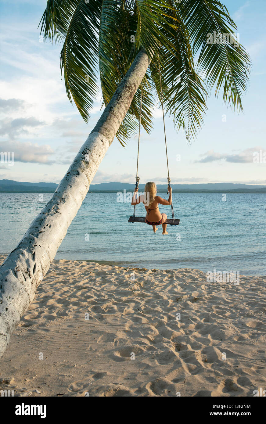 Vista posteriore della femmina in una spiaggia swing attaccato a un albero di palma in isole San Blas. Destinazione di viaggio, stile di vita / Concetto di vacanza. Panama, Ott 2018 Foto Stock