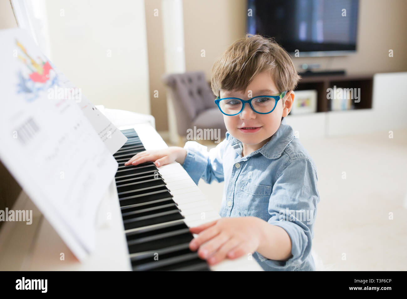 Little Boy guardando la telecamera durante la riproduzione di pianoforte. Foto Stock