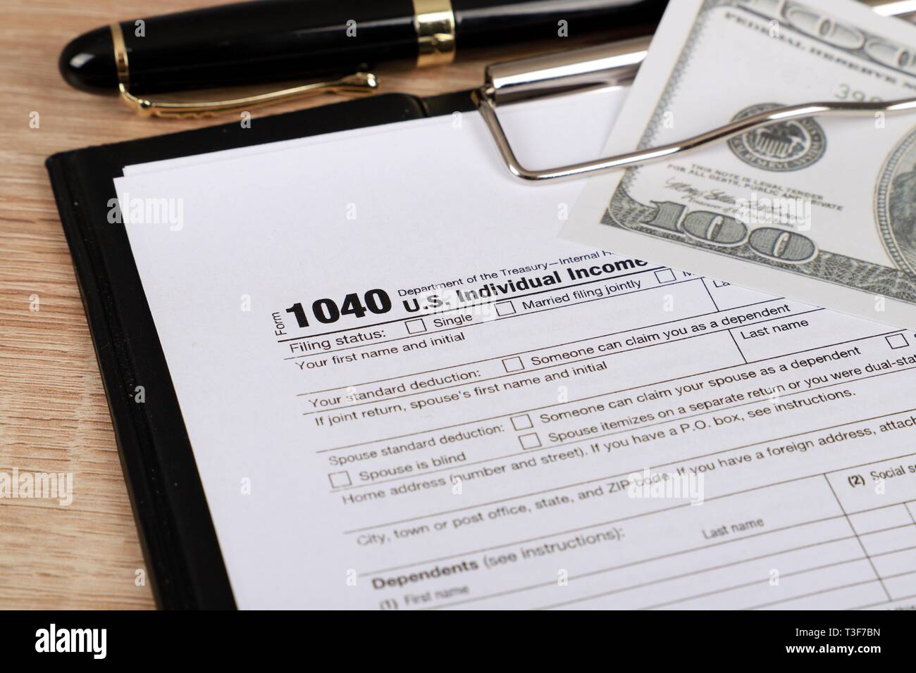 1040 forma fiscale - i singoli redditi forma 1040 si trova nei pressi di centinaia di dollari su un tavolo Foto Stock