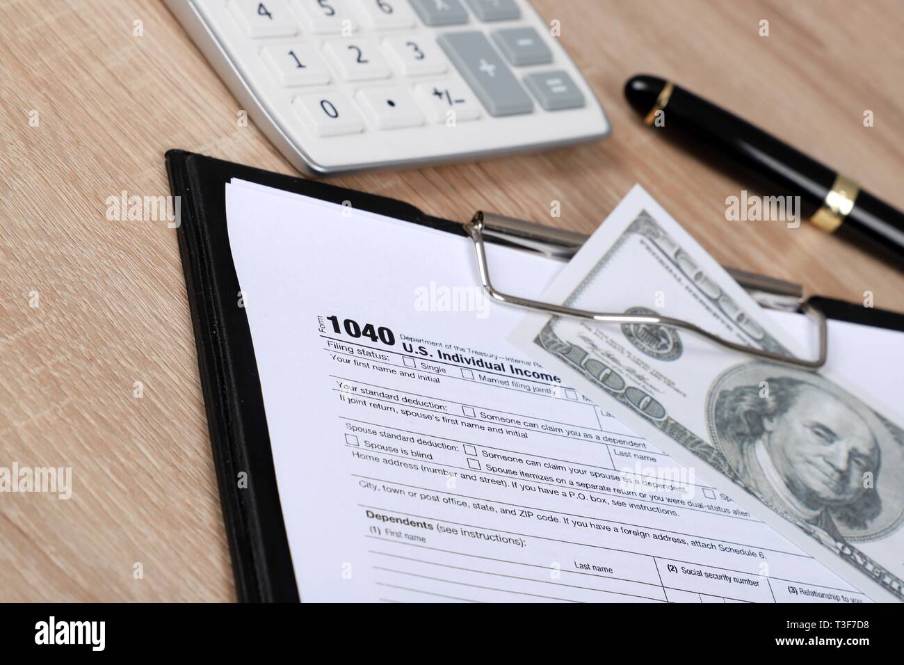 1040 forma fiscale - i singoli redditi forma 1040 si trova nei pressi di centinaia di dollari su un tavolo Foto Stock