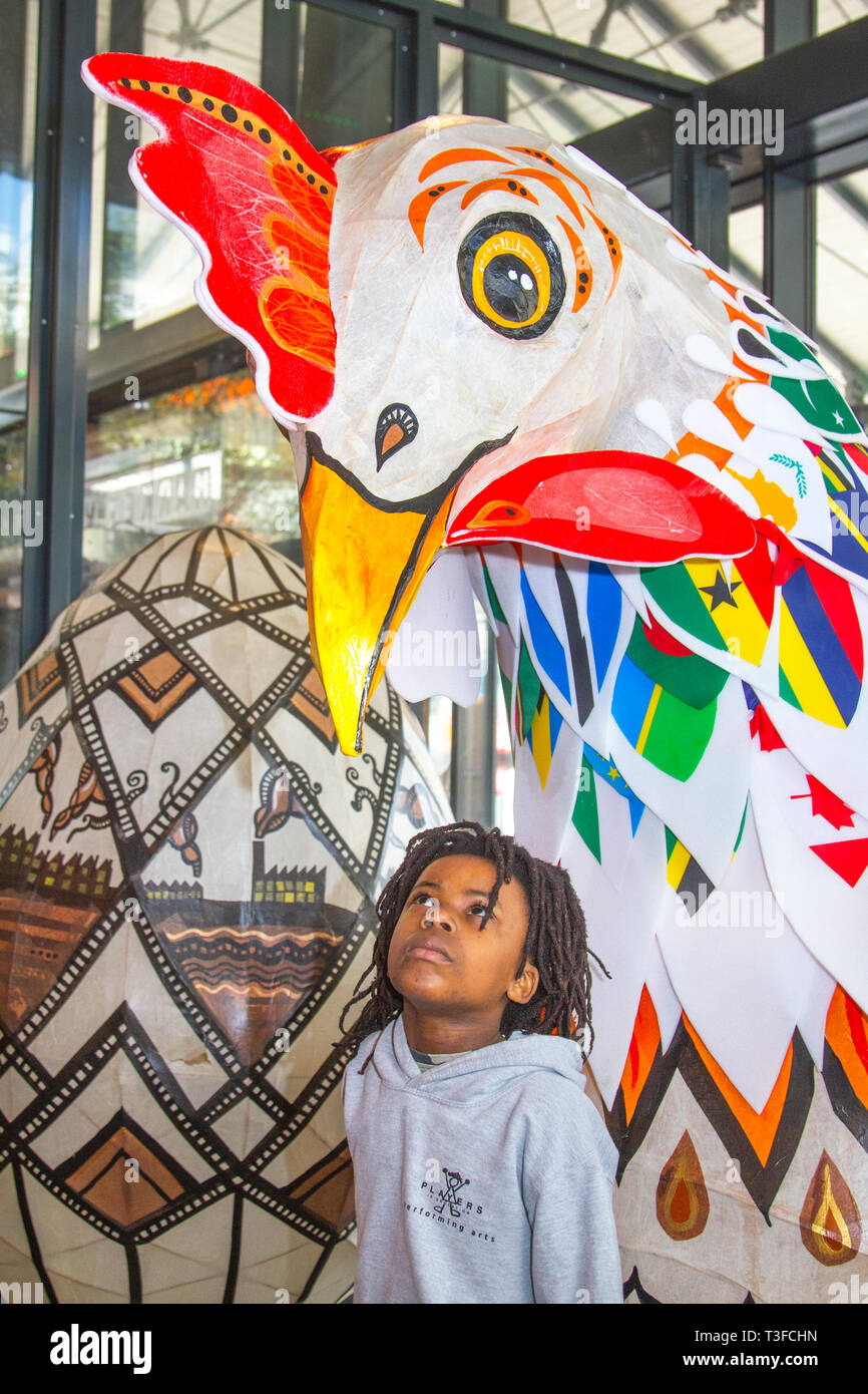 Gigantesco pollo di carta pasquale oversize in esposizione nel centro della città. TADIWA CHAPARADZA (MR) 10 anni è incuriosito dalla grande scultura di scarafaggio Papier-Mache. Le figure degli animali natalizi di Pasqua in mostra, alte due metri, le attrazioni sono collocate fuori dal mercato di Preston. Keith Ogden, un artista locale, è l'uomo dietro l'attrazione dipinta a mano. Le uova sono a tema intorno al patrimonio industriale della città e paesaggi Lancashire. I mercati di Preston espongono le uova di Pasqua giganti per la competizione di selfie durante le vacanze di Pasqua. Foto Stock