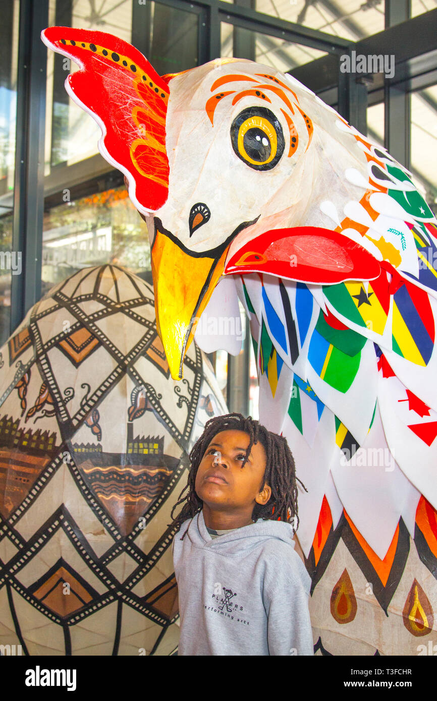 Gigantesco pollo di carta pasquale oversize in esposizione nel centro della città. TADIWA CHAPARADZA (MR) 10 anni è incuriosito dalla grande scultura di scarafaggio Papier-Mache. Le figure degli animali natalizi di Pasqua in mostra, alte due metri, le attrazioni sono collocate fuori dal mercato di Preston. Keith Ogden, un artista locale, è l'uomo dietro l'attrazione dipinta a mano. Le uova sono a tema intorno al patrimonio industriale della città e paesaggi Lancashire. I mercati di Preston espongono le uova di Pasqua giganti per la competizione di selfie durante le vacanze di Pasqua. Foto Stock