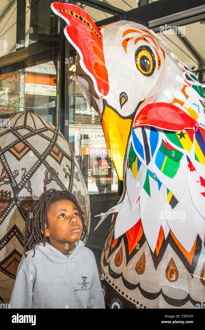 Gigantesco pollo di carta pasquale oversize in esposizione nel centro della città. TADIWA CHAPARADZA (MR) 10 anni è incuriosito dalla grande scultura di scarafaggio Papier-Mache. Le figure degli animali natalizi di Pasqua in mostra, alte due metri, le attrazioni sono collocate fuori dal mercato di Preston. Keith Ogden, un artista locale, è l'uomo dietro l'attrazione dipinta a mano. Le uova sono a tema intorno al patrimonio industriale della città e paesaggi Lancashire. I mercati di Preston espongono le uova di Pasqua giganti per la competizione di selfie durante le vacanze di Pasqua. Foto Stock