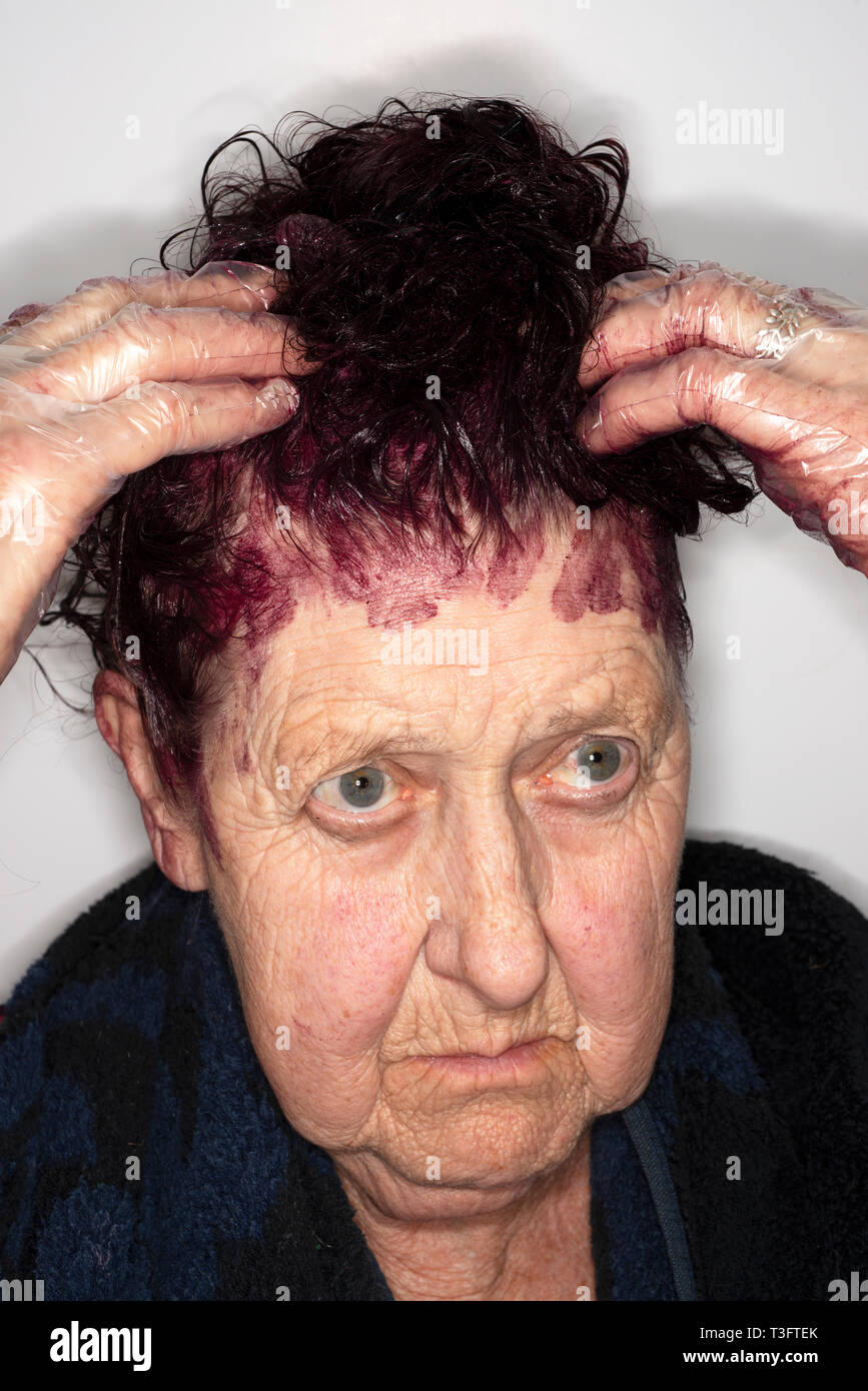 82-anno vecchia donna applicando tintura per capelli Foto Stock