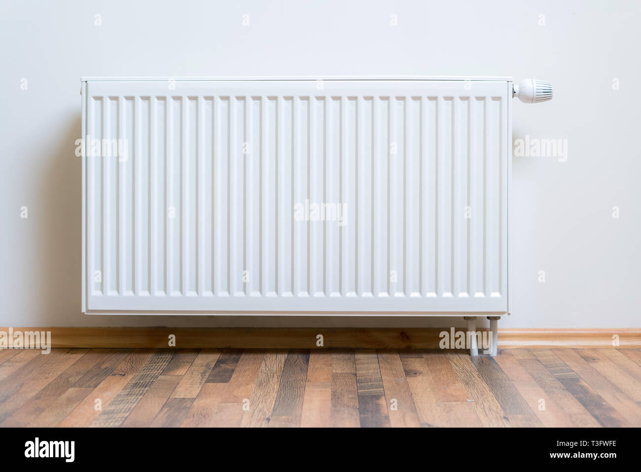 Home Radiatore riscaldatore sul muro bianco sul legno del pavimento di legno duro. Riscaldamento regolabile attrezzatura per appartamento e home Foto Stock