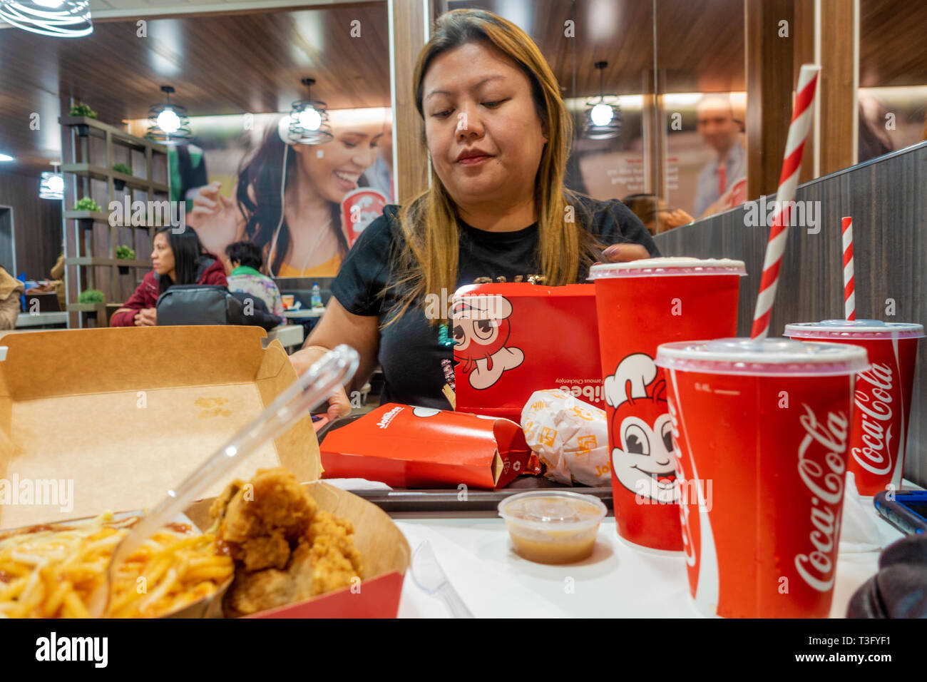 Una signora filippina gode di un pasto presso il Jollibee un ristorante fast food in Earls Court di Londra. Foto Stock