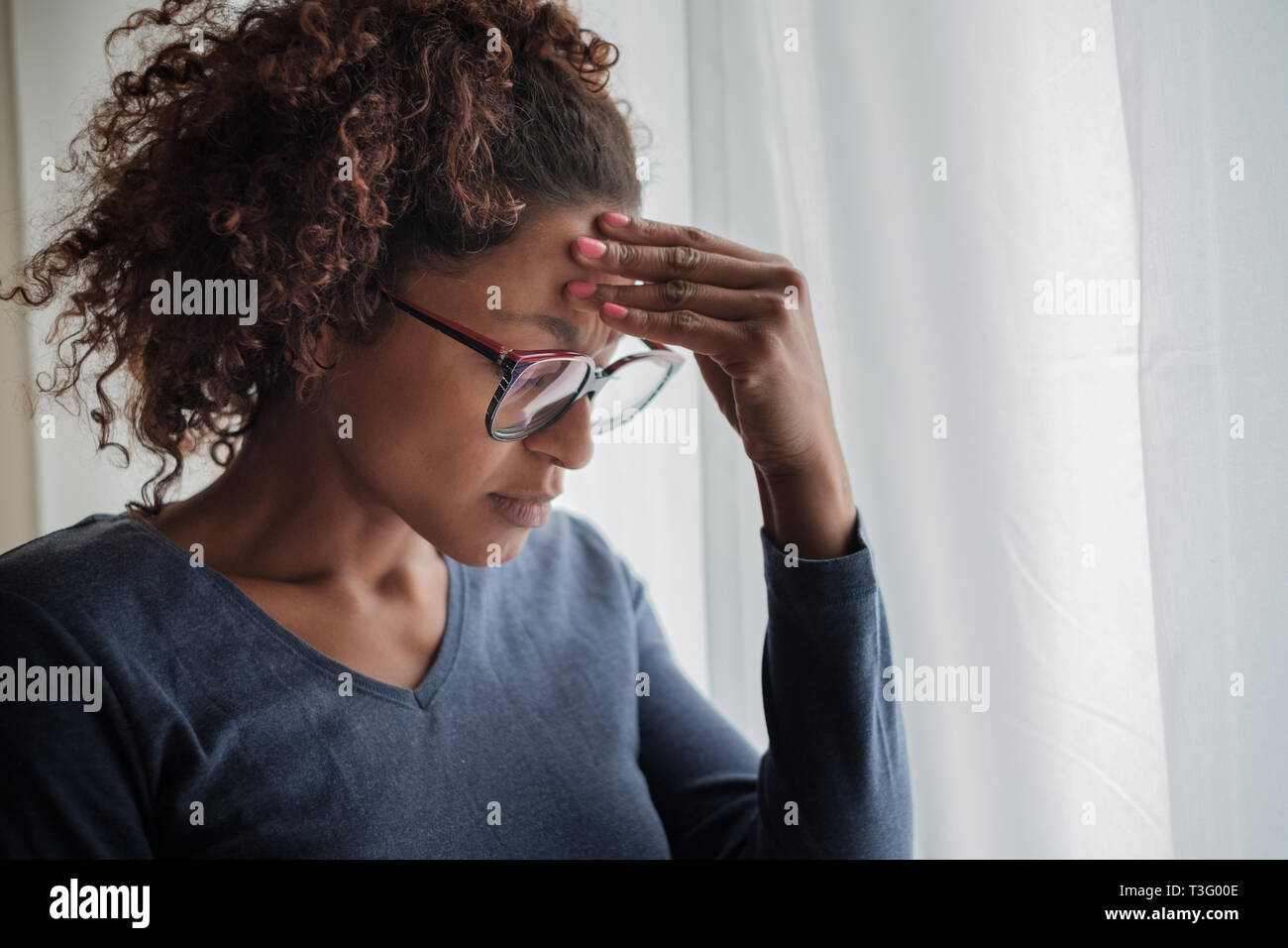 Ritratto di pensieroso nero donna in piedi accanto alla finestra Foto Stock