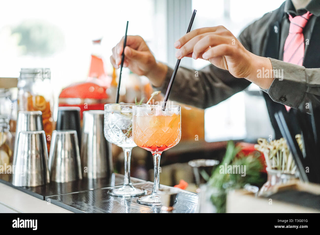 Il barista la preparazione di diversi cocktail miscelazione con cannucce bar interno - Professione, lavoro e concetto di stile di vita - Soft focus sulla sommità del primo bicchiere Foto Stock