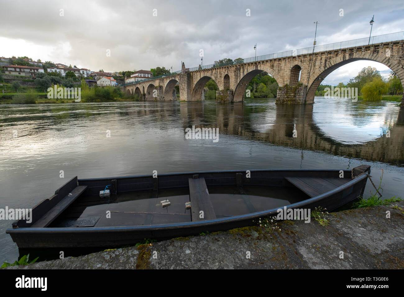 La barca di legno accanto al medievale Ponte di pietra sul fiume Lima in Ponte da Barca, Minho, Portogallo, Europa Foto Stock