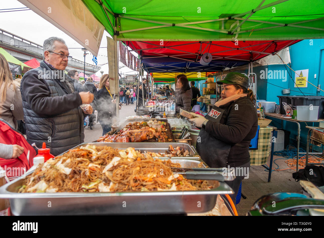 Un uomo acquista il cibo dalla cucina di strada venditore in Acklam villaggio sul Portobello Road a Notting Hill, Londra, Regno Unito Foto Stock