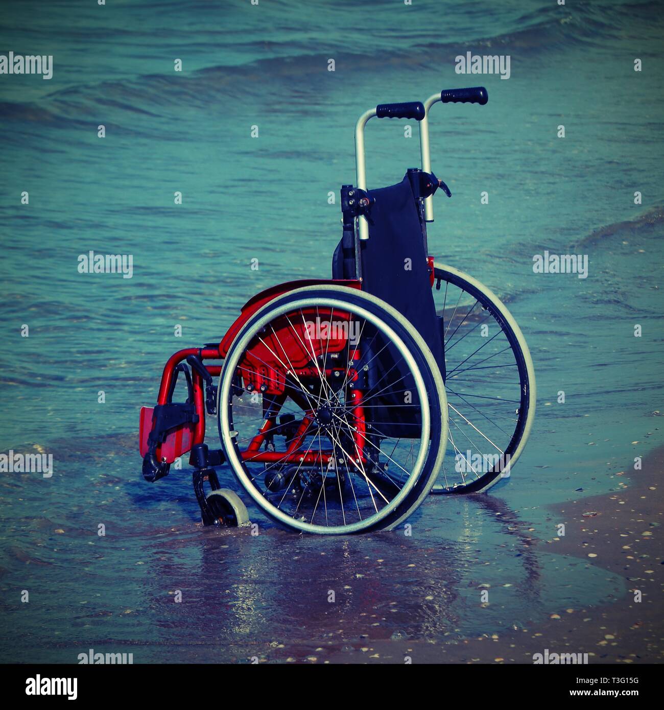 Sedia a rotelle sulla riva del mare in una calda giornata estiva con il vecchio effetto tonico, Foto Stock