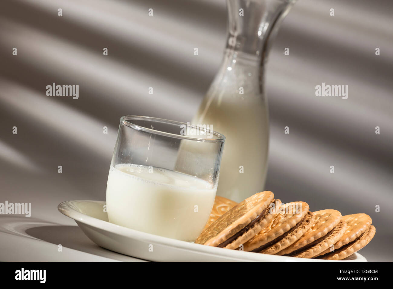 Il sole entra attraverso la serranda, prima colazione con latte e biscotti al cioccolato Foto Stock