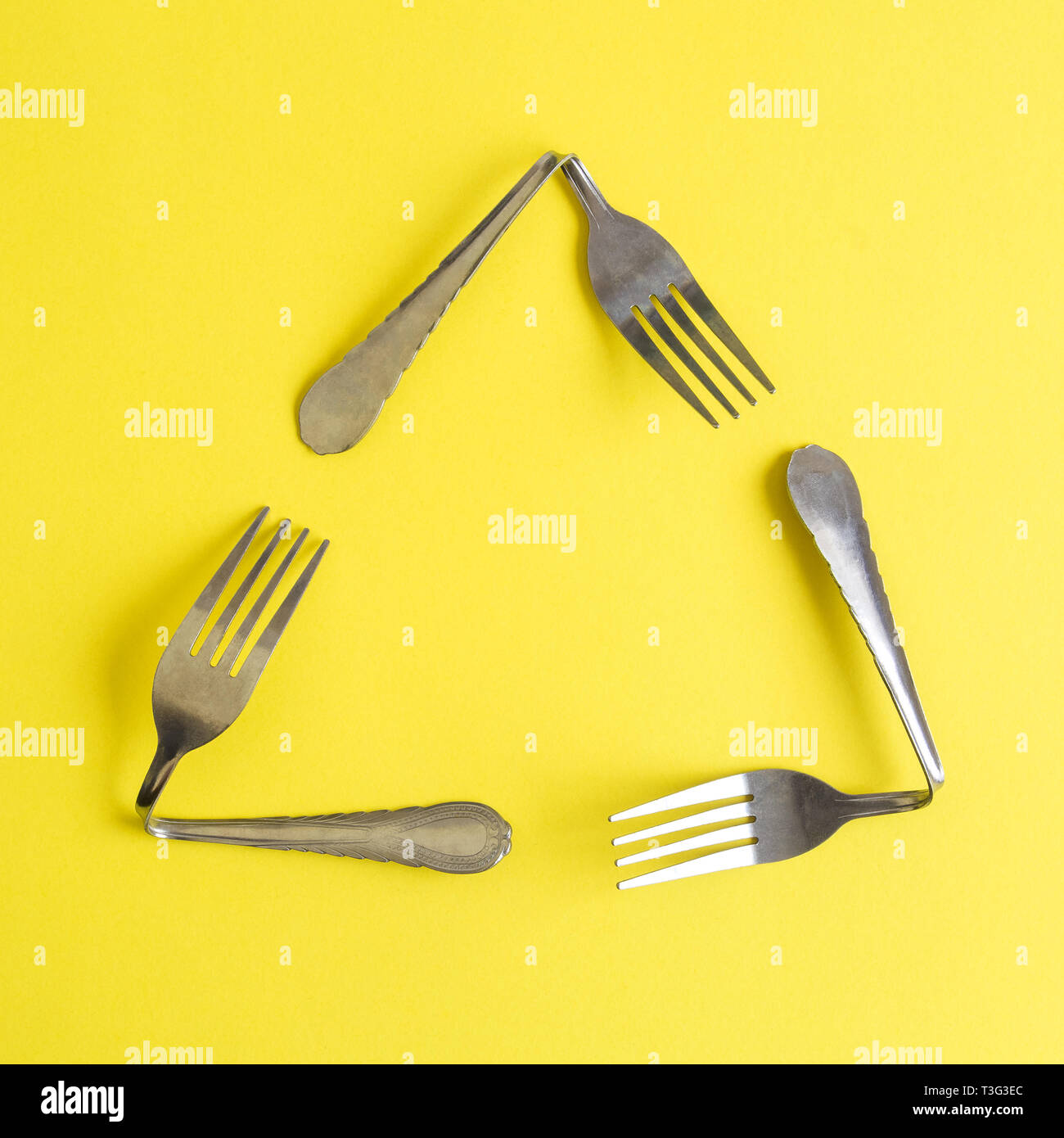 Triangolare riciclo eco icona resa delle forche su sfondo giallo ecologia minimo concetto creativo. Foto Stock