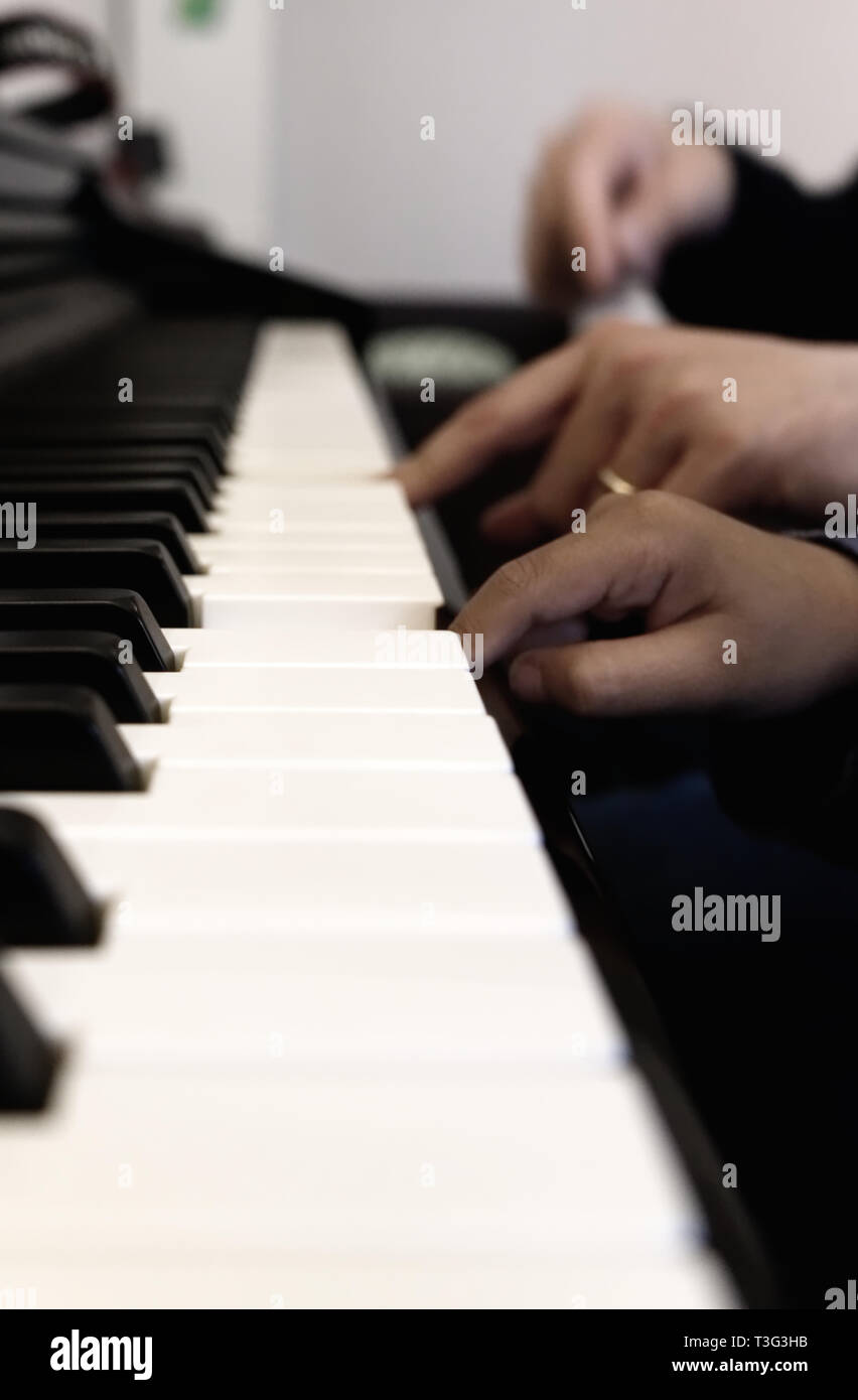 Piccole e grandi mani sulla tastiera del pianoforte senza facce. Foto Stock