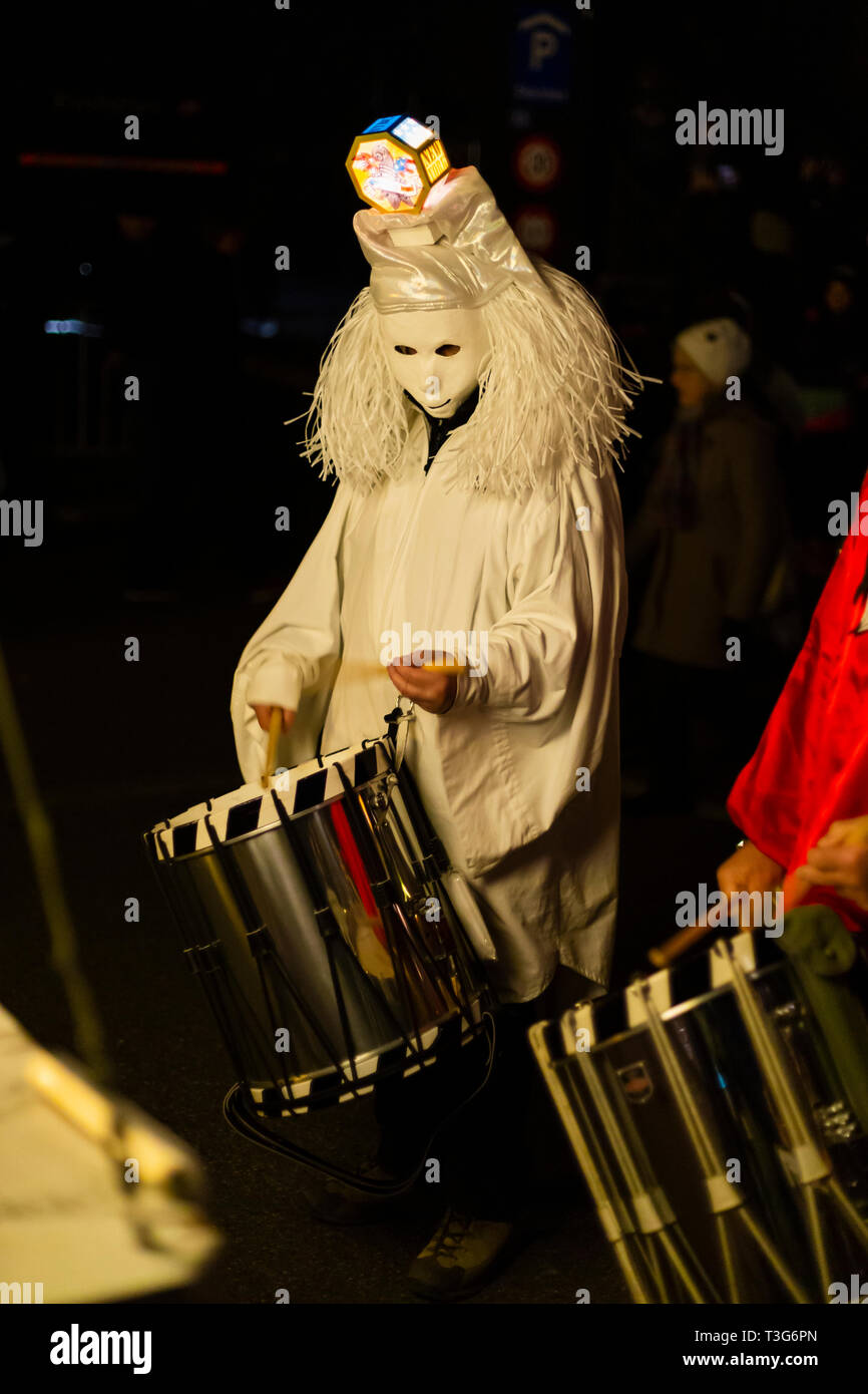 Marktgasse, Basilea, Svizzera - Marzo 11th, 2019. Unico batterista in un costume bianco durante il carnevale morgestraich parade Foto Stock