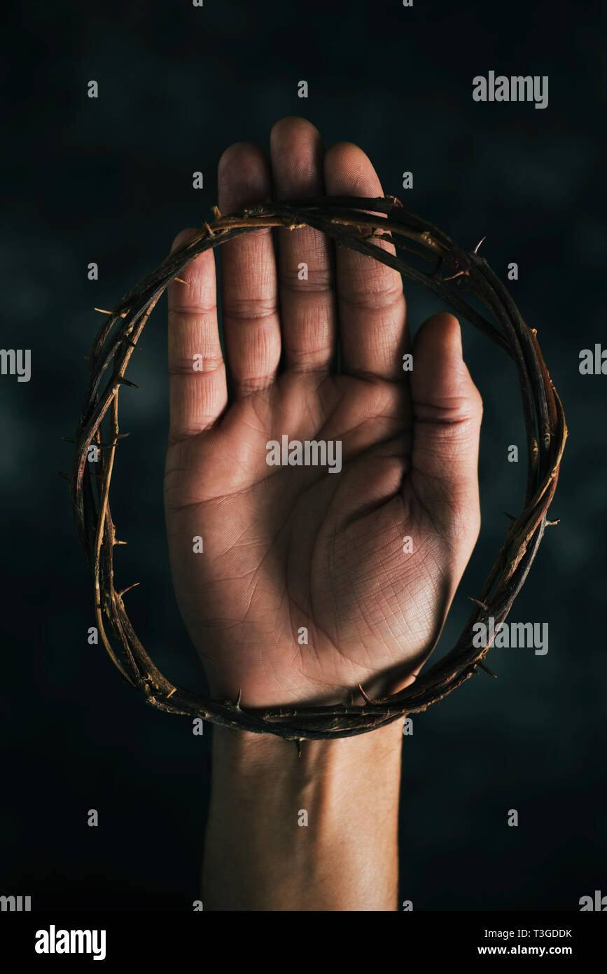 Angolo di alta vista di una corona di spine per la mano di un uomo, su sfondo scuro Foto Stock