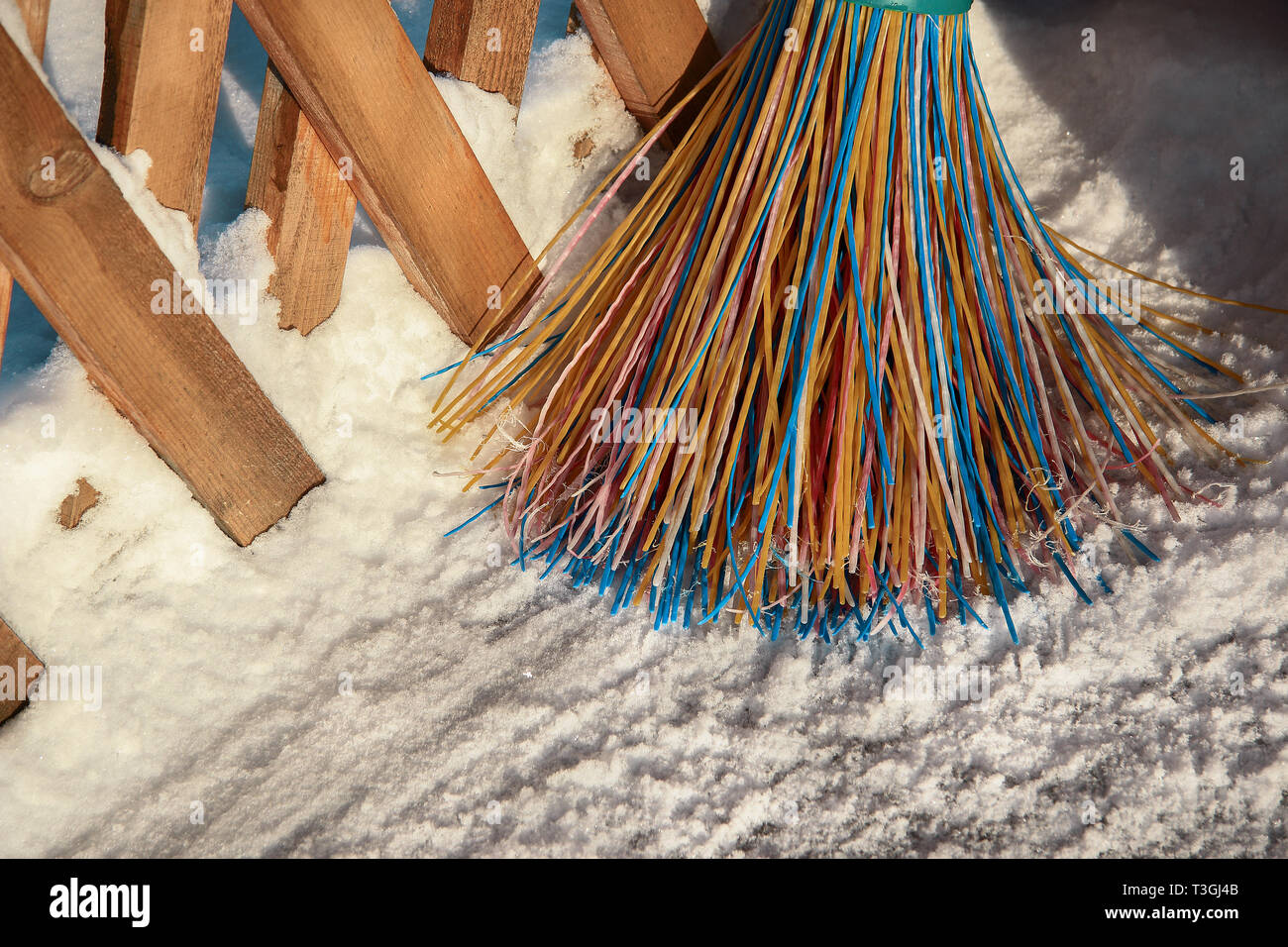 Una scopa in plastica con setole multicolore della pila si erge nella neve. Il concetto di pulizia dell'area di neve in inverno.Close-up di obj Foto Stock
