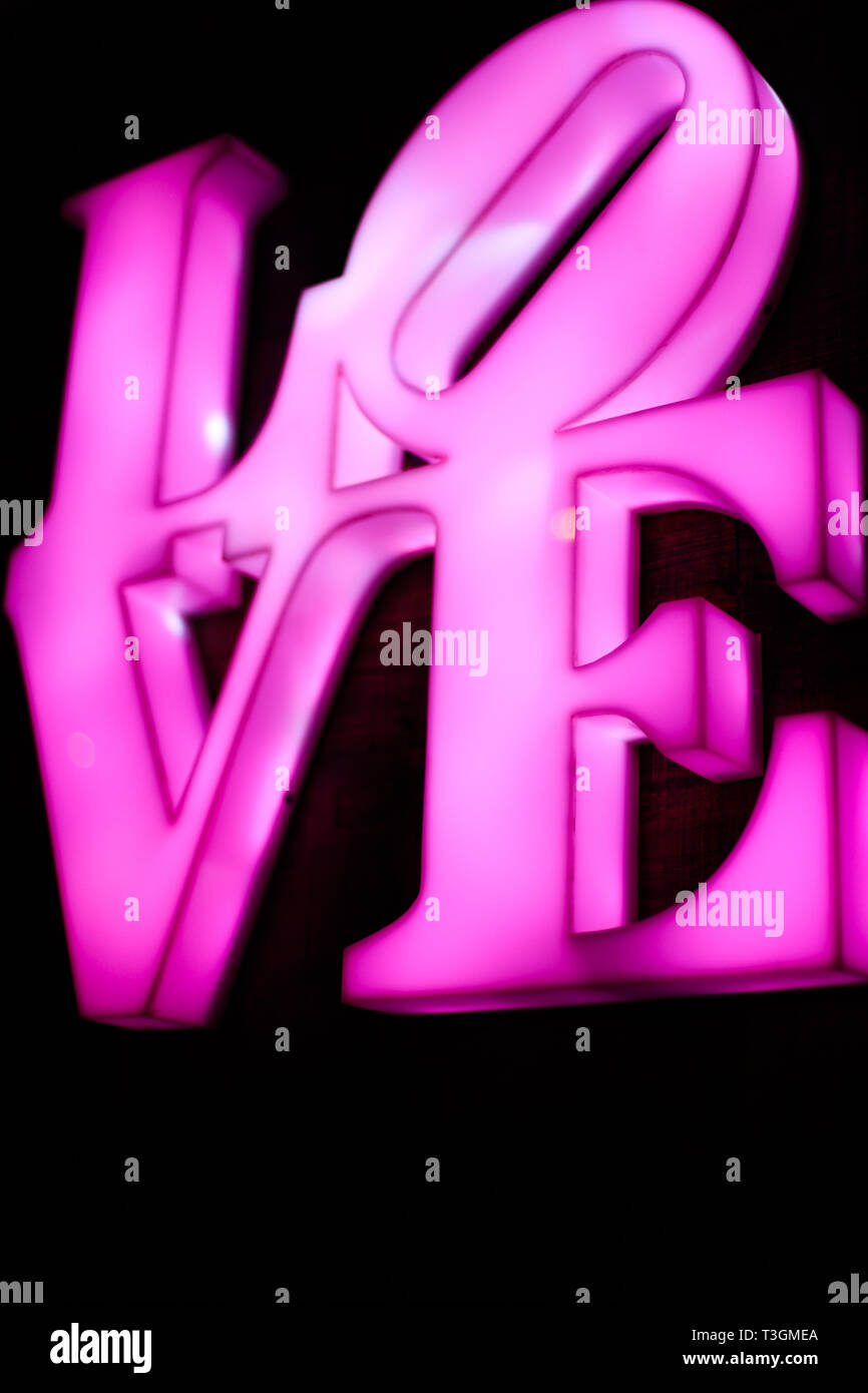 Abstact sfocate rosa in plastica segno della parola amore su sfondo nero. Trendy 80s concetto. Foto Stock