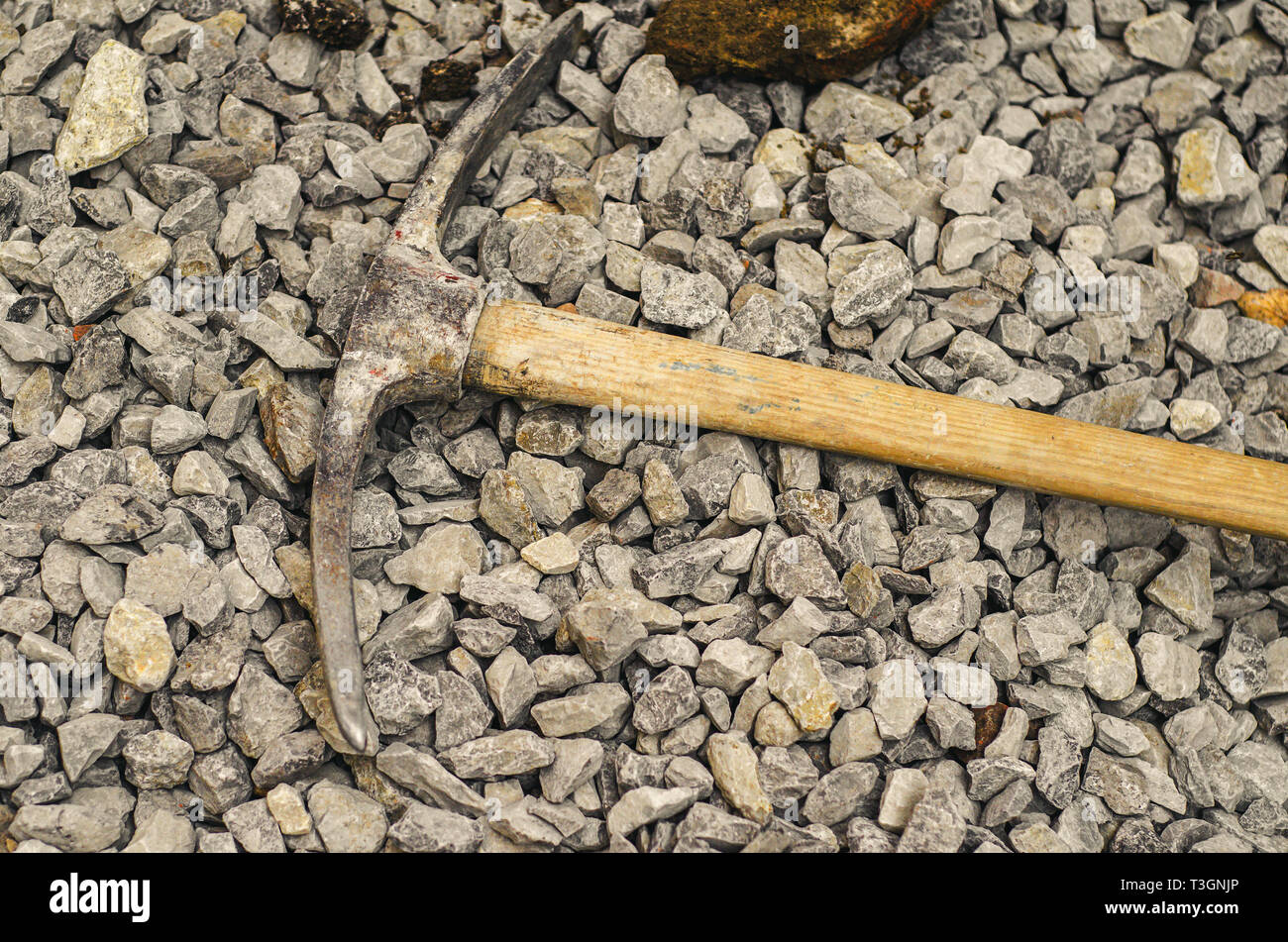 Piccone di metallo su un manico di legno su un mucchio di macerie di  piccole dimensioni. Sporco lavoro duro Foto stock - Alamy