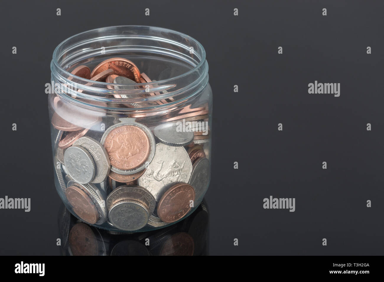 Contenitore di plastica contenente le monete del Regno Unito - come metafora per risparmi personali, Rainy day risparmio, risparmi pensionistici pot, salvataggio di pot. Foto Stock