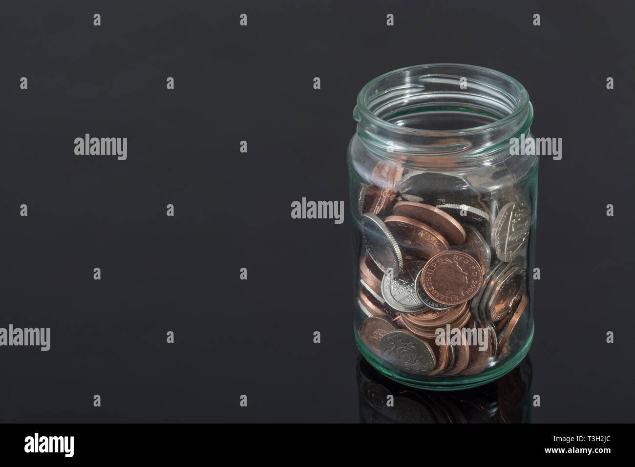 Il vasetto di vetro contenente le monete del Regno Unito - come metafora per risparmi personali, Rainy day risparmio, risparmi pensionistici pot, salvataggio di pot. Foto Stock