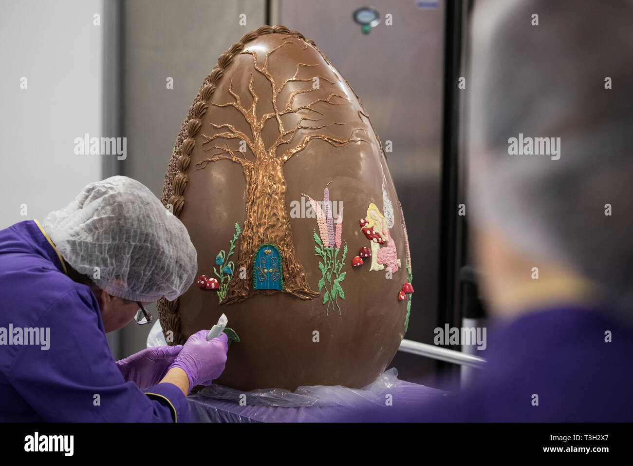Cioccolatieri decorare un gigantesco uovo di cioccolato a Cadbury World in Birmingham a celebrare la Pasqua. Foto Stock