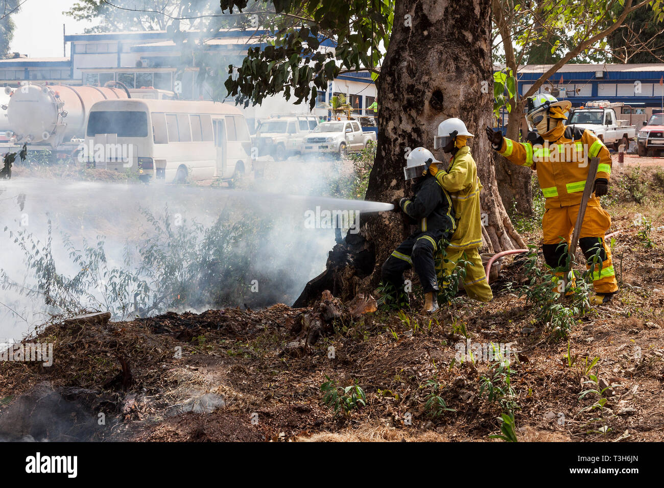 Sierra Leoneans nel team di risposta alle emergenze formazione in estinzione incendio fare pause tra boschi locali e comunità utilizzando i tubi flessibili da offerte Foto Stock