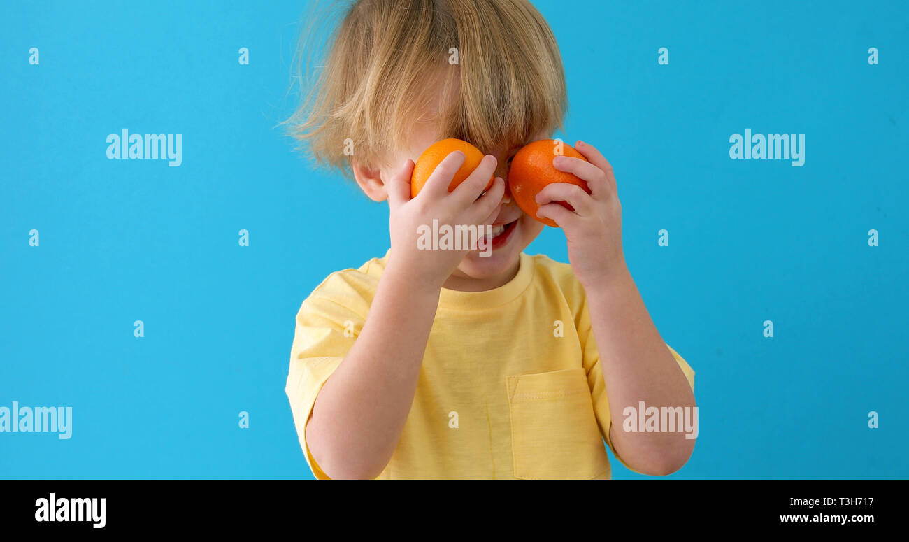 Il capretto con i tangerini. piccolo ragazzo con i mandarini Foto Stock