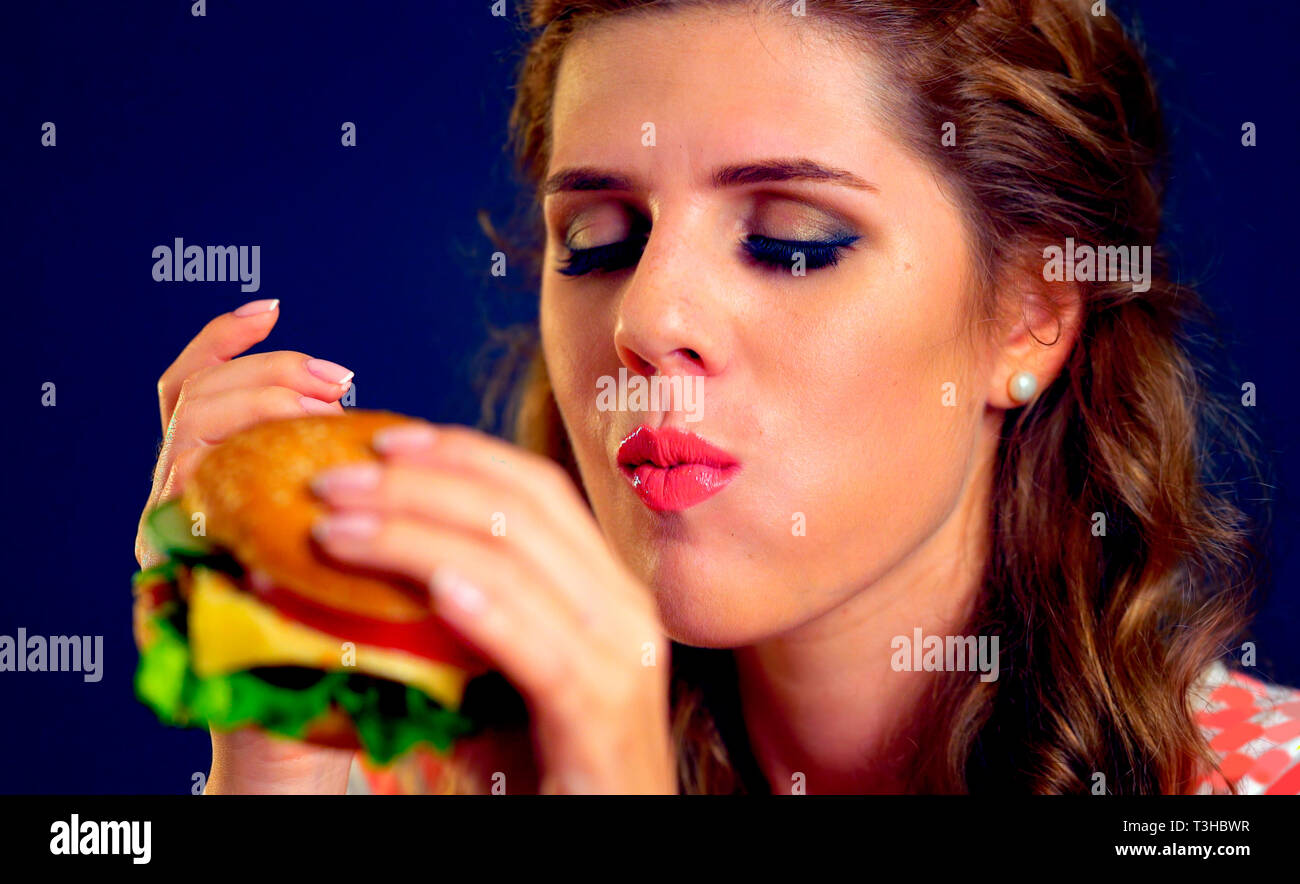 Donna mangiare hamburger fast food Foto Stock