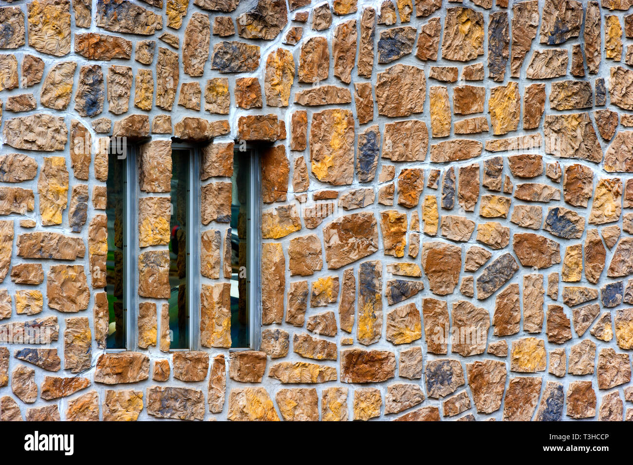 Tre strette finestre in un edificio esterno parete di roccia. Foto Stock