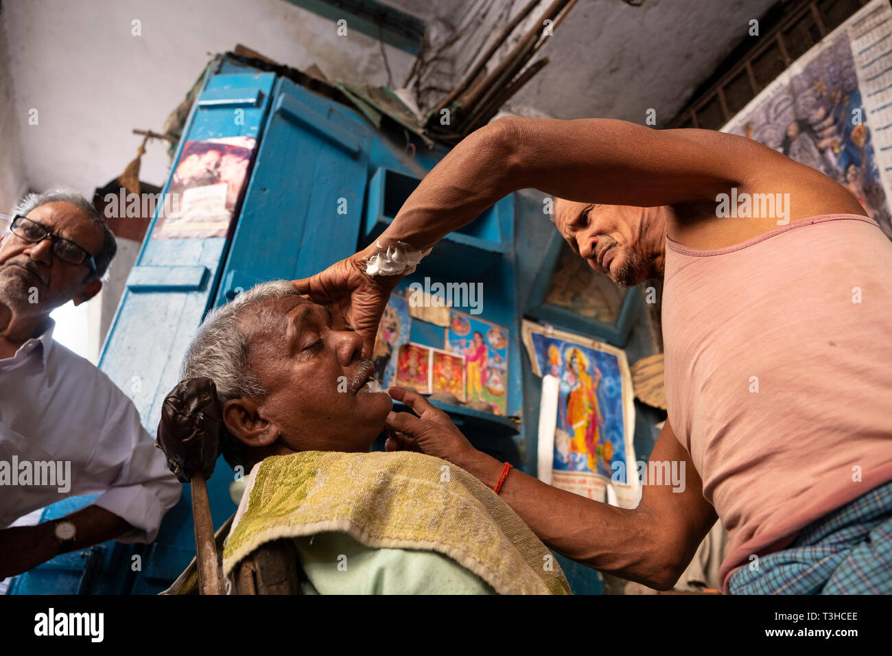 Barbiere in Kolkata dando un uomo una rasatura in un negozio per esterni Foto Stock