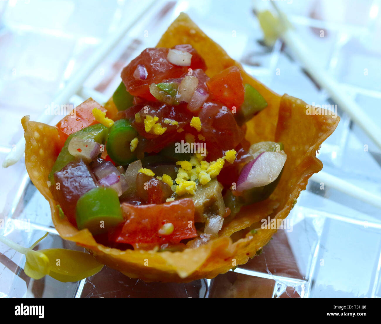 Tonno crudo con verdure e uova in una tortilla chip su fette di cetriolo Foto Stock