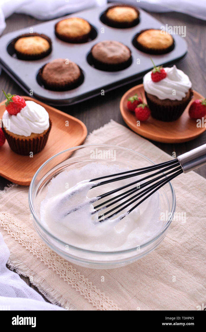 Facendo una tortina panna con una frusta. Foto Stock